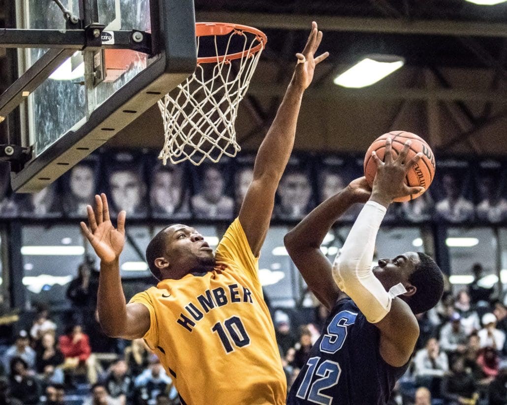 TORONTO, ON - NOV. 12, 2016: Tremaine Hibbert of the Sheridan Bruins tries to release a short jumper against Tyrone Dickson of the Humber Hawks.